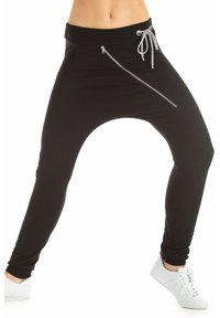 Black jogger pants made of stretchy fabric, featuring a drawstring waistband and a zippered pocket on the side. Fitted at the ankles.