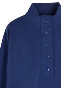Granatowa koszula polo z wysokim kołnierzykiem, wyposażona w cztery błyszczące guziki oraz teksturowany materiał. Projekt jest prosty i nowoczesny.