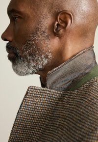 Wool blend coat with a textured brown and blue pattern, featuring a brown inner collar and green accents. The design is tailored with a structured fit.