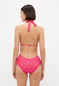 Ροζ φλοράλ μπικίνι με δέσιμο στον λαιμό, ψηλόμεσο κάτω μέρος και επαναλαμβανόμενο μοτίβο λουλουδιών. Λείο, ελαστικό υλικό.