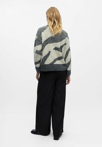 Maglione lavorato a maglia spessa in grigio e bianco sporco, con un audace motivo astratto. Vestibilità ampia con polsini e orlo a coste, realizzato in misto lana.