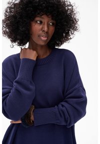 Marineblauwe gebreide trui met een ronde halslijn en geribbelde manchetten. Zachte textuur, losse pasvorm en opvallend stiksel op de stof.