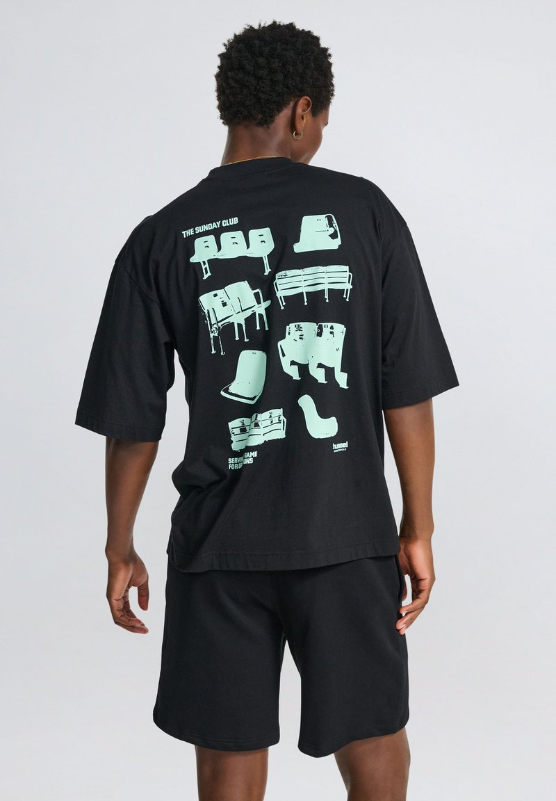 Svart oversized t-shirt med en mintgrön grafisk illustration av olika stolar och bänkar på baksidan. Rund halsringning och korta ärmar.