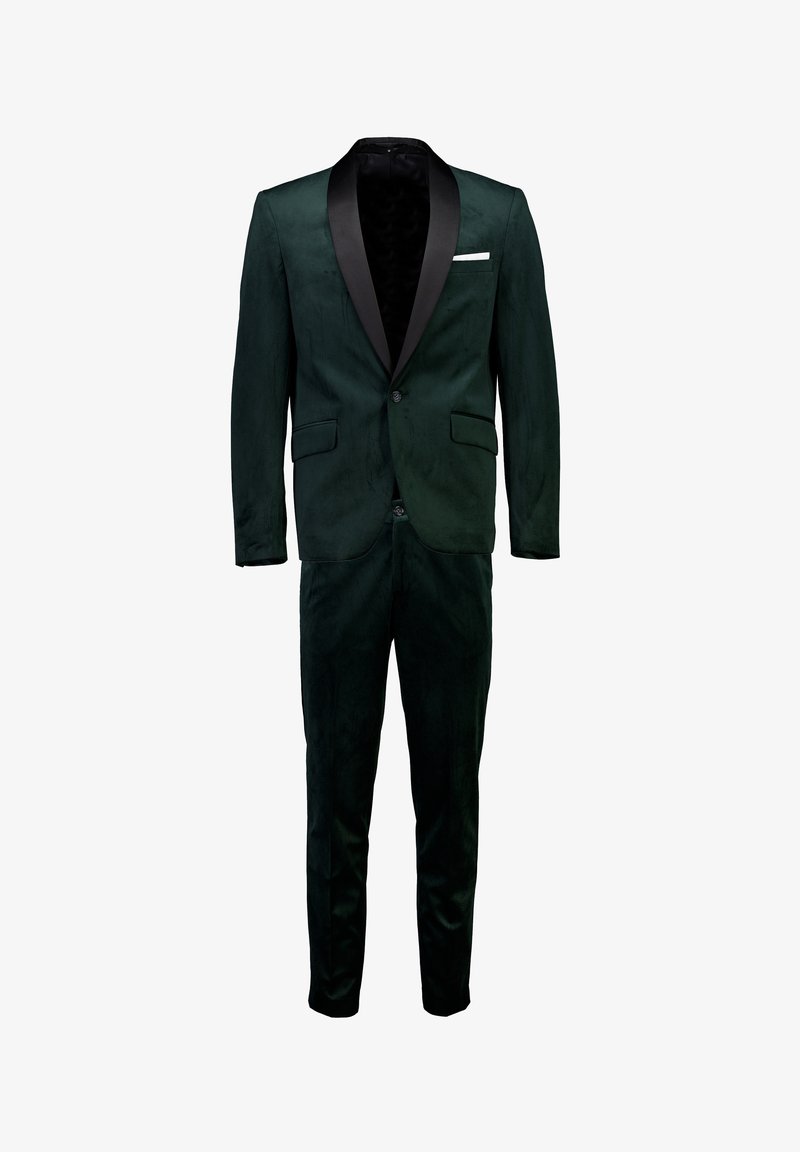 Completo verde in velluto con colletto sciallato in satin nero, design slim fit, due tasche frontali e chiusura con un solo bottone. Presenta un fazzoletto bianco nella tasca.