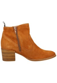 Botte en daim beige montant à la cheville avec fermeture éclair latérale, bout arrondi et talon bloc en bois superposé sur fond blanc.