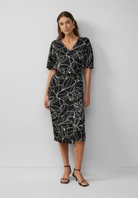 Robe noire avec un décolleté en V et des manches courtes, ornée d'un motif botanique blanc. Le tissu a une texture lisse et une taille ceinturée.