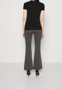 Černé krátké rukávy přiléhavé tričko v kombinaci se šedými zvonovými kalhotami, vyrobenými z měkkého materiálu, se hladkým povrchem a jemnou pružností.