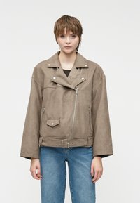 Brun semsket skinnjakke med bred krage, asymmetrisk glidelås og sidelommer; har belted midje og avslappet passform.