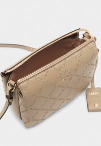 Borsa a tracolla in pelle beige con un motivo logo testurizzato, accessori in oro e chiusura con zip. Interno in tessuto marrone. Include una tracolla regolabile.
