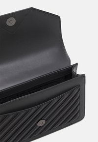 Portafoglio in pelle nera con un motivo testurizzato a righe su un lato e una finitura liscia sull'altro. Presenta una chiusura a scatto e più scomparti.