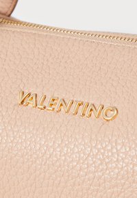 Svetlo roza usnjena torbica z teksturirano površino, zlatim okovjem in vtisnjenim logotipom "VALENTINO". Zipper zapiranje na vrhu.