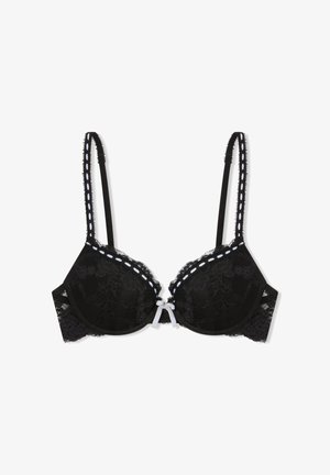 Reggiseno in pizzo nero con coppe imbottite, decorazione con cuciture bianche lungo i bordi, spalline regolabili e un piccolo fiocco bianco al centro davanti.