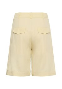 Shorts beige mi-genoux avec passants pour ceinture et deux poches arrière à rabat, vus de dos sur un fond blanc.
