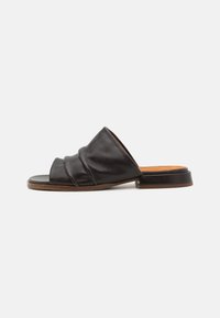 Sandal in pelle nera con tre pieghe morbide sulla parte superiore, punta aperta e tacco basso a blocco. Superficie liscia e soletta beige chiaro.