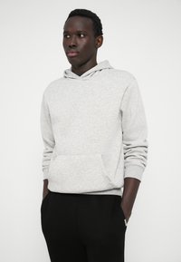 Gray hooded sweatshirt with a kangaroo pocket and ribbed cuffs, made from soft fabric, paired with black pants. Simple, casual design.