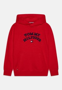 Hoodie en coton rouge avec un grand logo brodé "TOMMY HILFIGER" en bleu marine, poche avant, et manches à bords-côtes avec accents de logo.