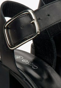 Zwarte hoge hak sandalen met een glanzende zilveren gesp, glad leer en een gestructureerde band, voorzien van een gevoerd voetbed en een gebosst logo.