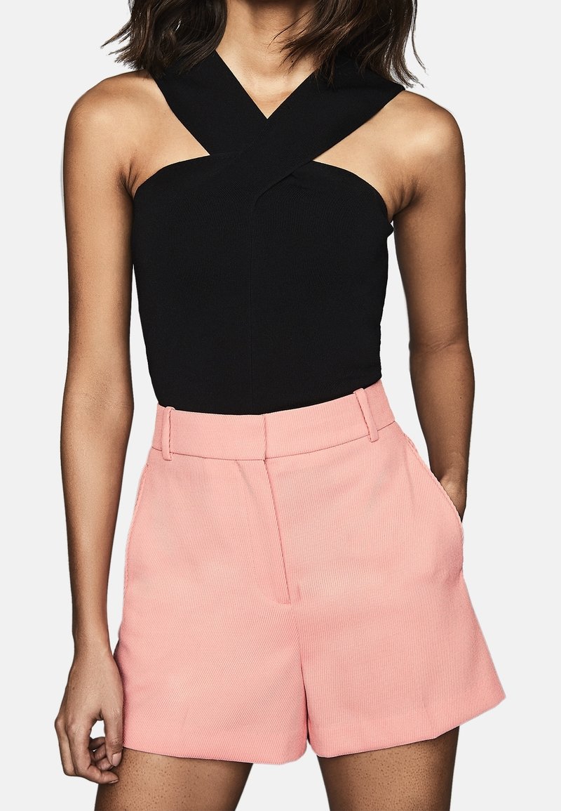Body negro sin mangas con tirantes cruzados y pantalones cortos de tiro alto rosas, con un tejido texturizado y bolsillos laterales.