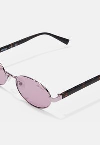Occhiali da sole rotondi con lenti rosa, montatura in metallo e bracci a fantasia tartarugata. Presentano un logo sulla tempia e naselli regolabili.