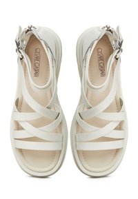 White strappy sandals made from smooth synthetic material, featuring a cushioned footbed, adjustable buckle, and sleek, contemporary design.