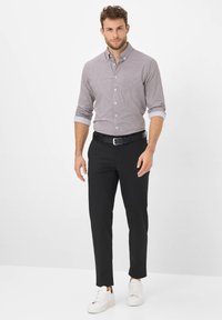 Camicia con bottoni in motivo a quadretti piccoli, grigia e bianca; abbinata a pantaloni neri aderenti e sneakers bianche, con cintura nera.