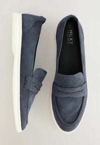Námornícke semišové slip-on mokasíny s bielou gumovou podrážkou. Má zvýraznené švy a hladký dizajn špičky. Ľahký a neformálny štýl.