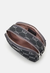 Neceser de tela negra texturizada con cremalleras plateadas, compartimentos internos y un sutil patrón de logotipos. Forrado con un suave material marrón claro.