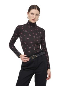Maglione a collo alto nero con stampa floreale rosa, maniche lunghe, design slim-fit. Abbinato a pantaloni neri a vita alta e una cintura con fibbia dorata.