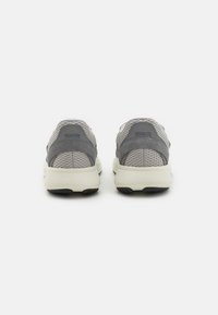 Gray athletic shoes featuring a mix of mesh and suede materials, with a solid black outsole and a cushioned white midsole.