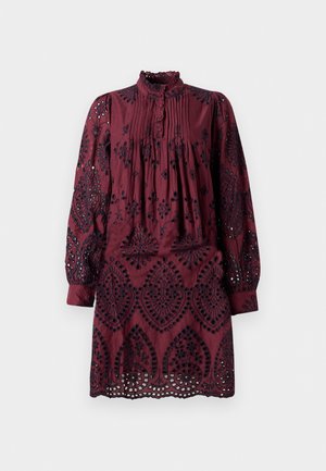 Burgunderkjole med lange ermer, plisserte front, volangkrage og intrikate svarte broderimønstre. Hullet cutouts langs kanten.