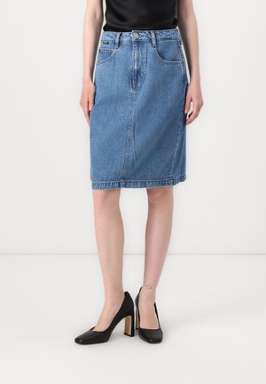 Blå denim midi-skjørt med rett snitt, frontlommer og en kant som når rett over kneet, kombinert med svarte høyhælte sko.