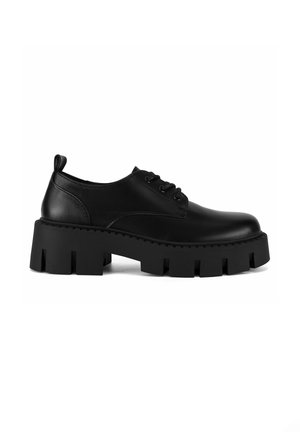 Chaussure noire en cuir à lacets avec semelle plateforme épaisse présentant des rainures profondes, vue de côté sur fond blanc.