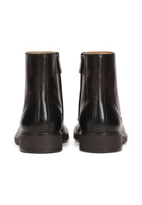 Botas de cuero negro hasta el tobillo con un acabado suave, que presentan un tacón bajo y grueso, y cremalleras laterales para facilitar su uso.