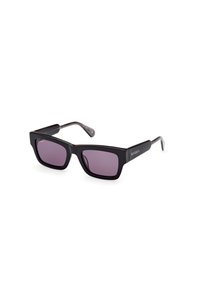 Gafas de sol rectangulares negras con lentes tintados en púrpura, que presentan montura gruesa y mate con acentos metálicos en las varillas. Patillas texturizadas.