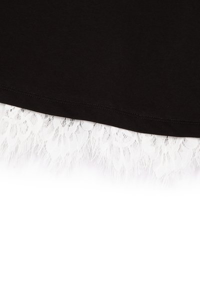 Top de tela negra con un dobladillo que presenta intrincados detalles en encaje blanco, exhibiendo un delicado patrón floral y bordes con flecos.
