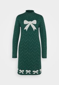 Grön stickad klänning med hög halskrage. Har en vit rosett-design i mitten och små vita prickar över hela. Accentuerad med vita rosetter i fållen.