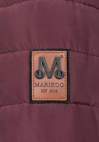 Bordeauxkleurige pufferjack met een rechthoekig bruin leren label met een reliëflogo "M" en de tekst "MARIKOO EST 2016." De textuur is glad en pufachtig.