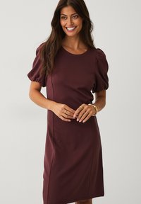 Weinrotes Kleid mit Puffärmeln, rundem Ausschnitt, figurbetonender Passform, strukturiertem Stoff, knielangem Design und sichtbaren Seitennähten.