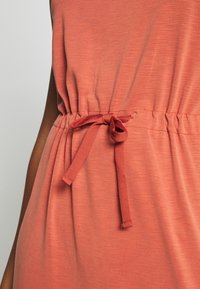 Ruskean värinen mekko, jossa on kerätty vyötärö ja solmittava nauha. Kangas näyttää pehmeältä ja siinä on hieman teksturoitu pinta.