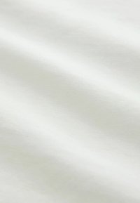 Tessuto bianco testurizzato con un aspetto liscio e morbido, che mostra leggere ondulazioni e una leggera lucentezza sulla superficie.