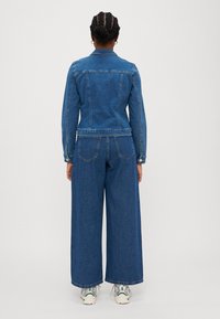 Jeansjacka med lång ärm och klassisk krage, matchad med vida denimbyxor. Blått tyg, synlig söm och femficksdesign.