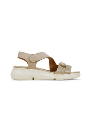 Sandali beige con una fascia metallica dorata e chiusura regolabile in velcro. Suola bianca imbottita con un motivo testurizzato per una migliore aderenza.