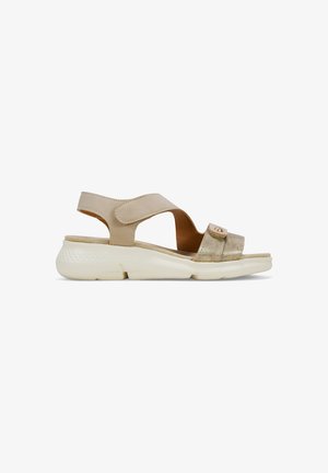 Sandales beiges avec une lanière métallique dorée et une fermeture réglable en velcro. Semelle blanche rembourrée avec un motif texturé pour une meilleure adhérence.