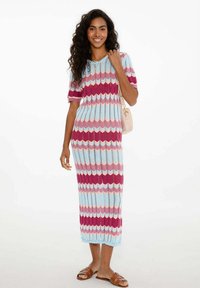 Sukienka dzianinowa do kolan, prążkowana, z wzorem w zygzak w odcieniach niebieskiego, różowego i magenty. Krótkie rękawy uzupełniają luźny krój.