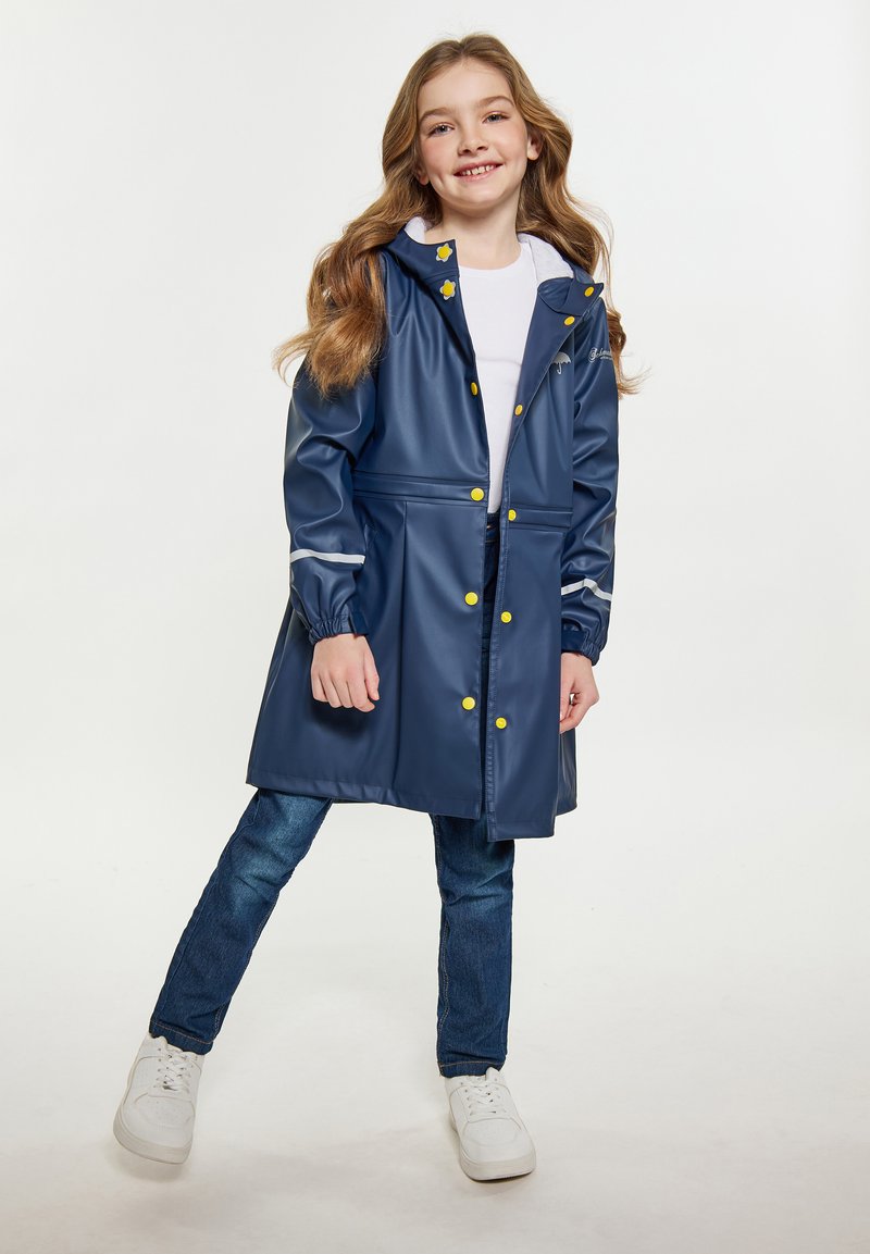 Mornarska dežna plašča iz sijočega materiala z rumenimi gumbi. Ima kapuco s vezalkami in elastične manšete, oblikovana je s prilegajočim pasom.