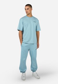 Ανοιχτό μπλε βαμβακερό μπλουζάκι και κολλαριστό παντελόνι με ριμπ λεπτομέρειες. Απλός σχεδιασμός, με ένα μικρό λογότυπο στο στήθος και στο παντελόνι.