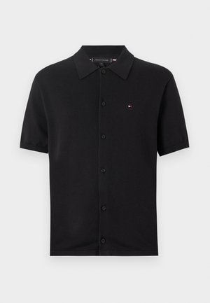Zwarte polo met korte mouwen van gladde katoen, voorzien van een knoopsluiting aan de voorkant en een klein geborduurd logo in rood, wit en blauw.