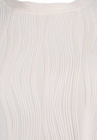 Ljust tyg top med vertikala, texturerade veck. Mjuk, flödande design med en subtil lyster, som ger en minimalistisk estetik.