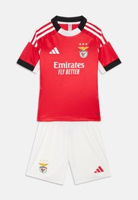 Raudona futbolo marškiniai su juodais akcentais, trys baltos juostos ant pečių ir komandos logotipas. Balti šortai su logotipu ir raudonais akcentais. Pagaminta iš kvėpuojančio audinio.