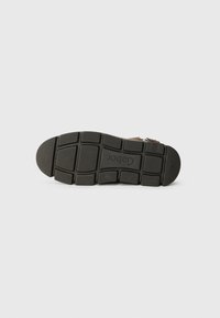 Suola di scarpa in gomma nera con un motivo testurizzato e scanalature rettangolari; logo "Cabot" inciso vicino al centro e accenti circolari.